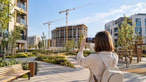 Посетитель фотографирует строящийся корпус жилого комплекса с общественной дорожки